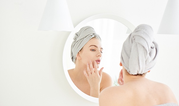 Woman looking in mirror, noticing signs of aging